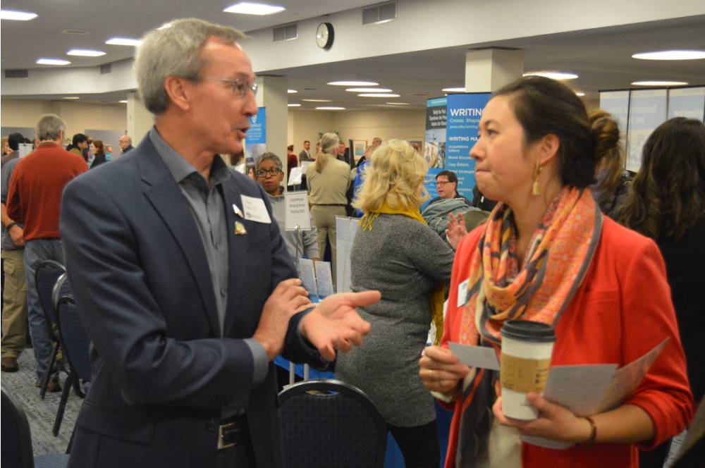 Two alumni talk to one another at the Academic Major Fair.